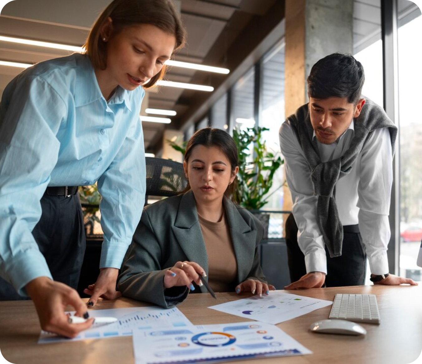 Three colleagues reviewing reports and dashboards together at a desk
