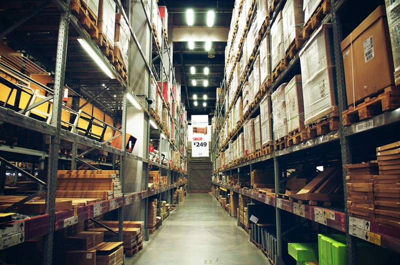 A brightly lit warehouse aisle stacked with inventory