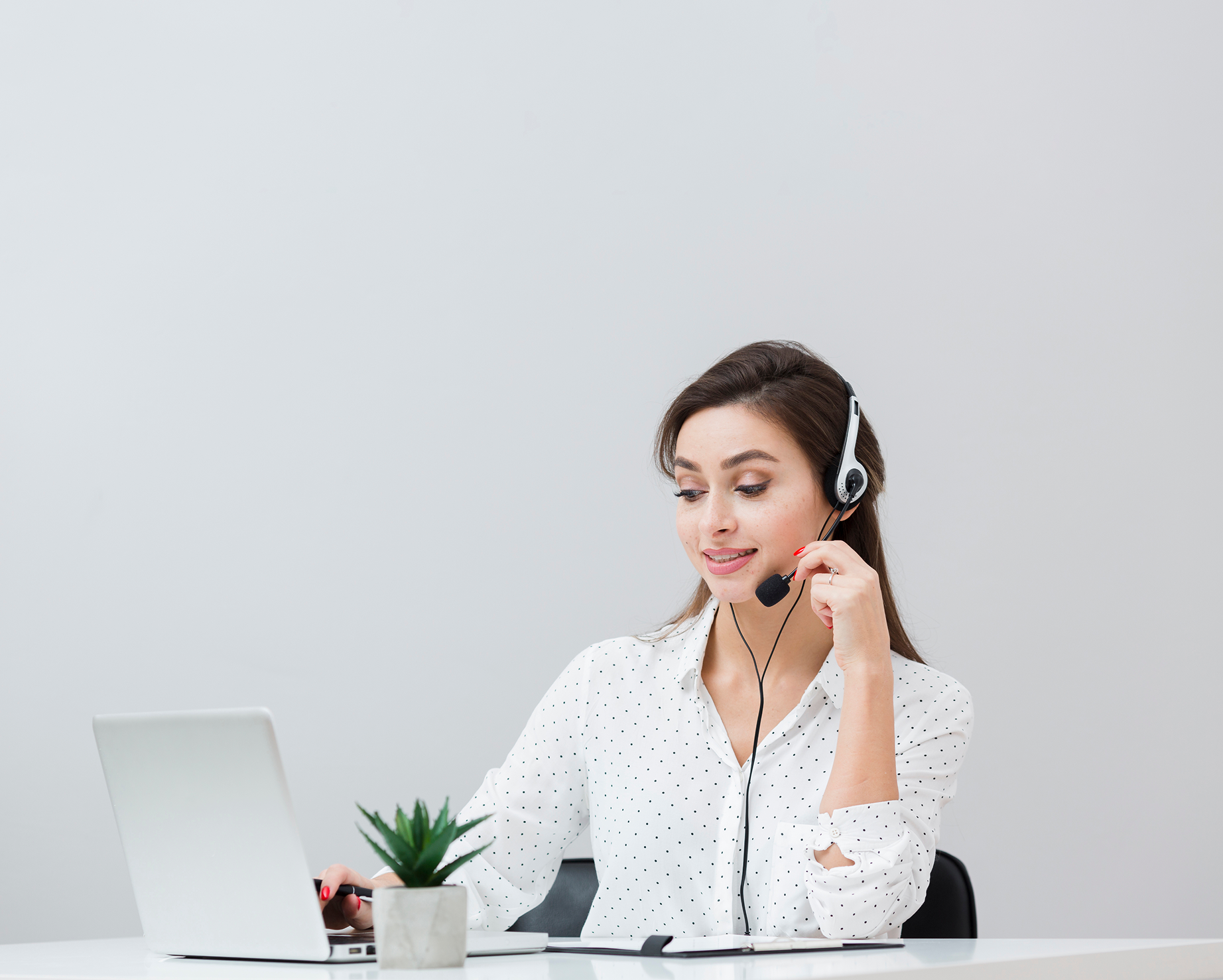 A person wearing a headset speaks while working at a laptop.